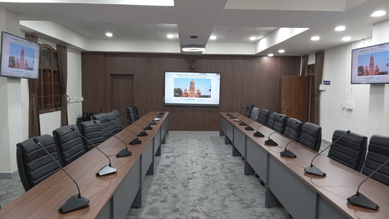 The 23-seat hybrid committee room at MSU Baroda — a U-shaped conference table in walnut finish, executive leather chairs along both delegate banks, and the gooseneck delegate discussion system.